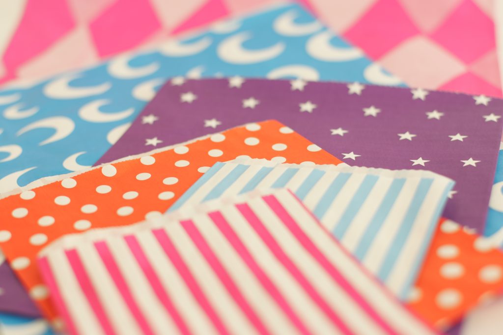 Close-up of colourful paper counter bags with fun prints, lying flat