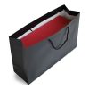 Large landscape black luxury paper gift bag with black rope handles holding a red shoe box.